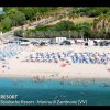 Spiaggia affollata con ombrelloni blu e mare azzurro.